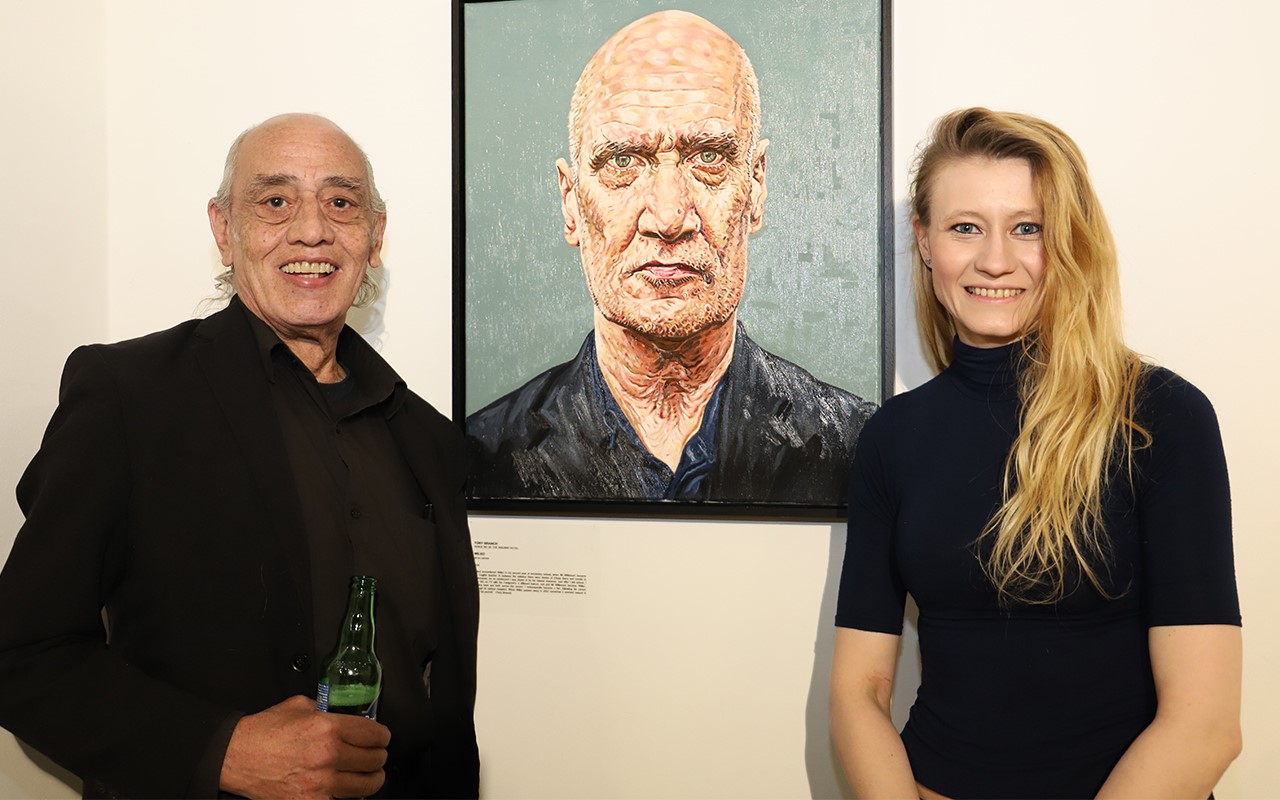 Man and lady by a portrait of a man